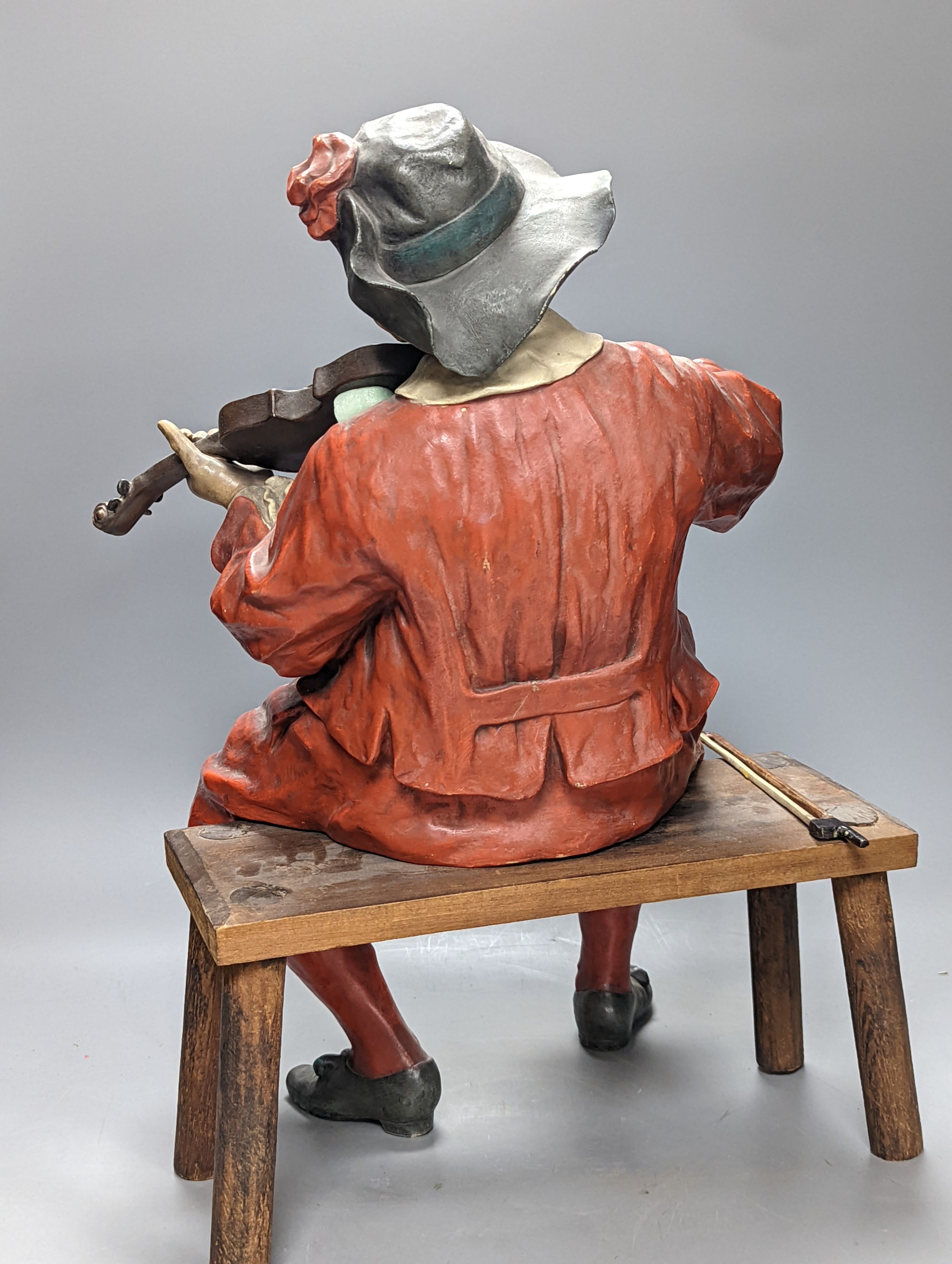 A pair of late 19th/early 20th century Austrian cold painted terracotta figures of musicians in 17th century dress, seated on wood stools 46cm